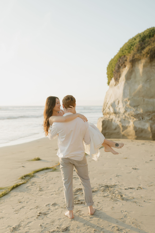 man holding woman on the beach