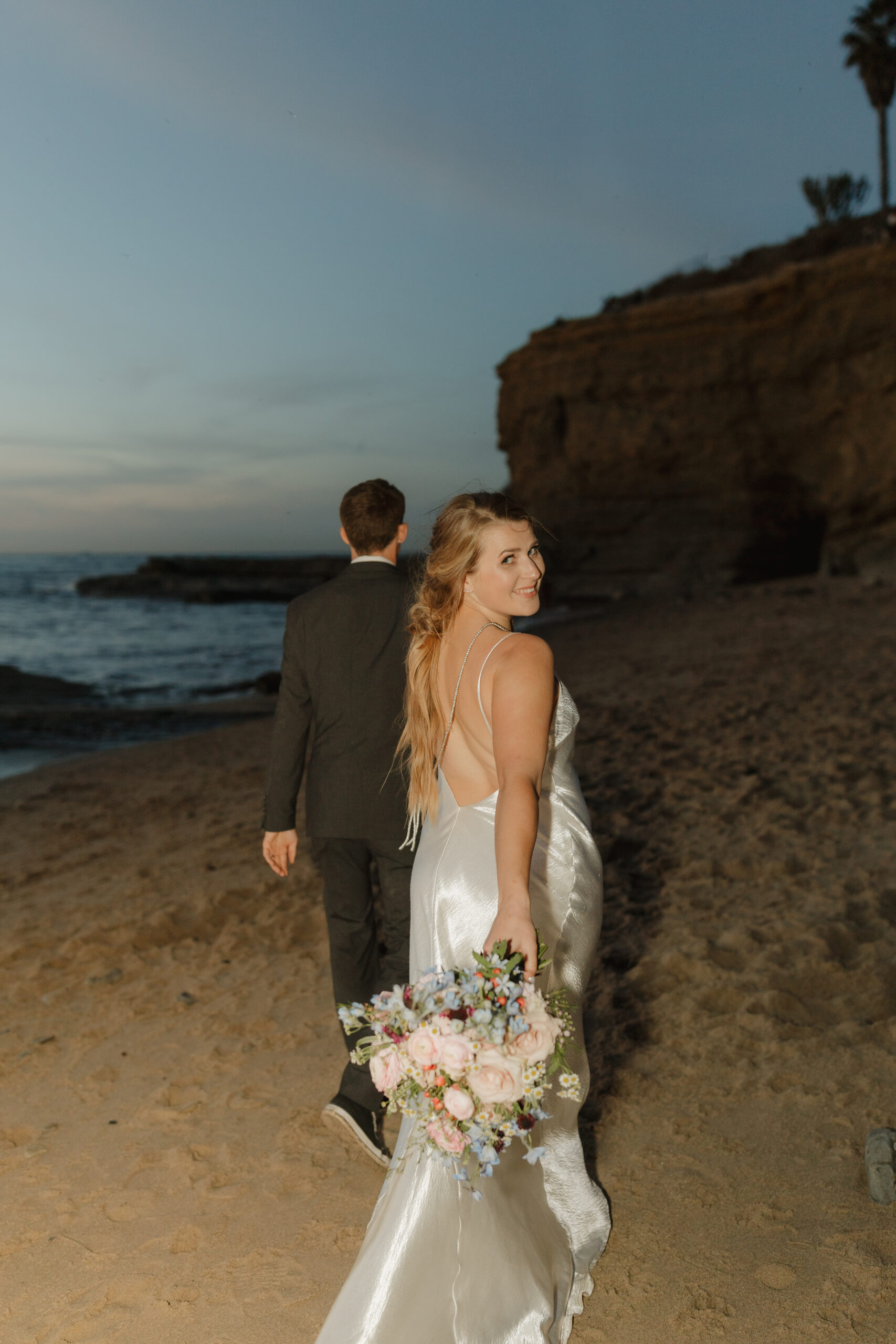 Sunset cliffs elopement couple walking down the beach after sunset