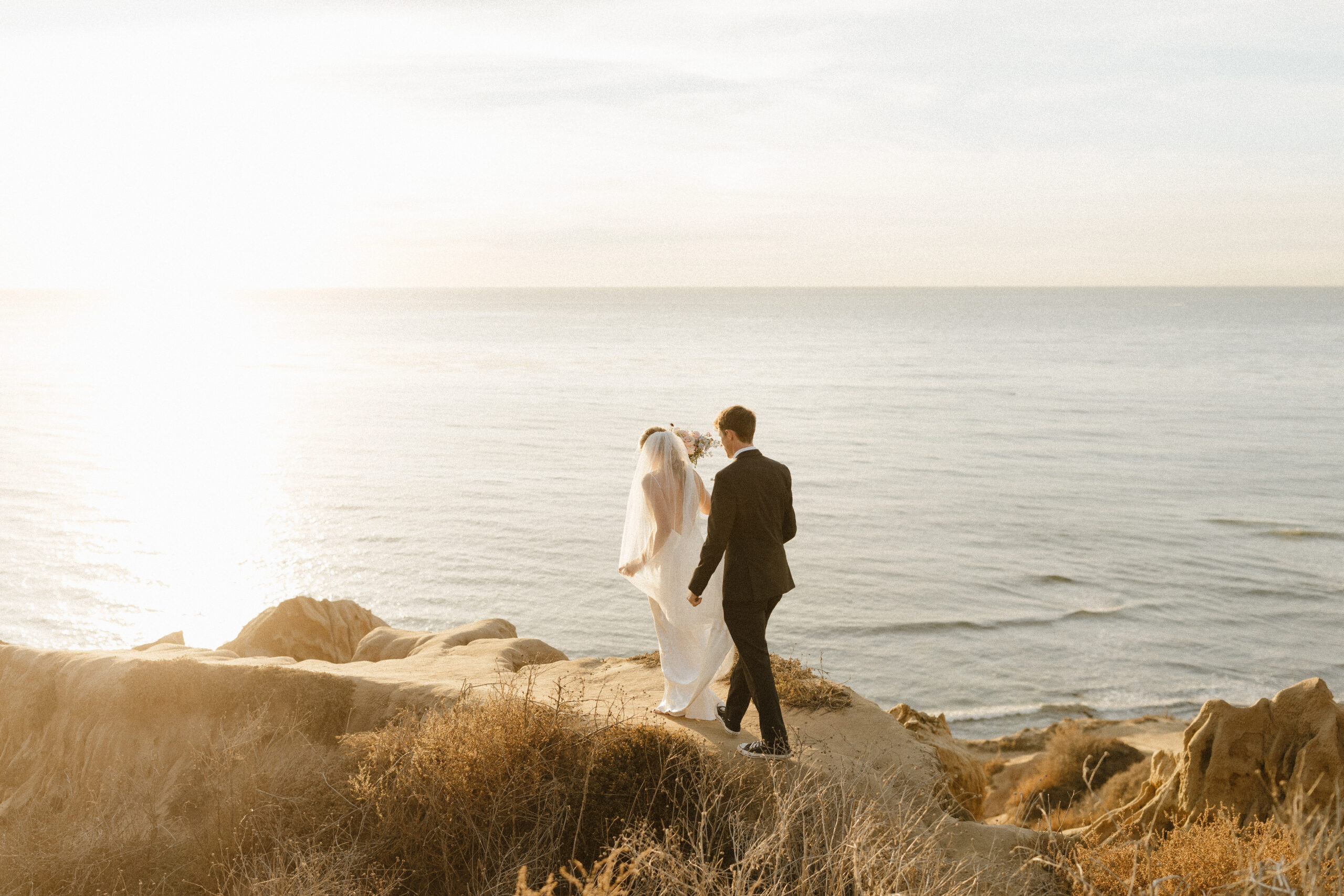 bride and groom walking atop the cliffs