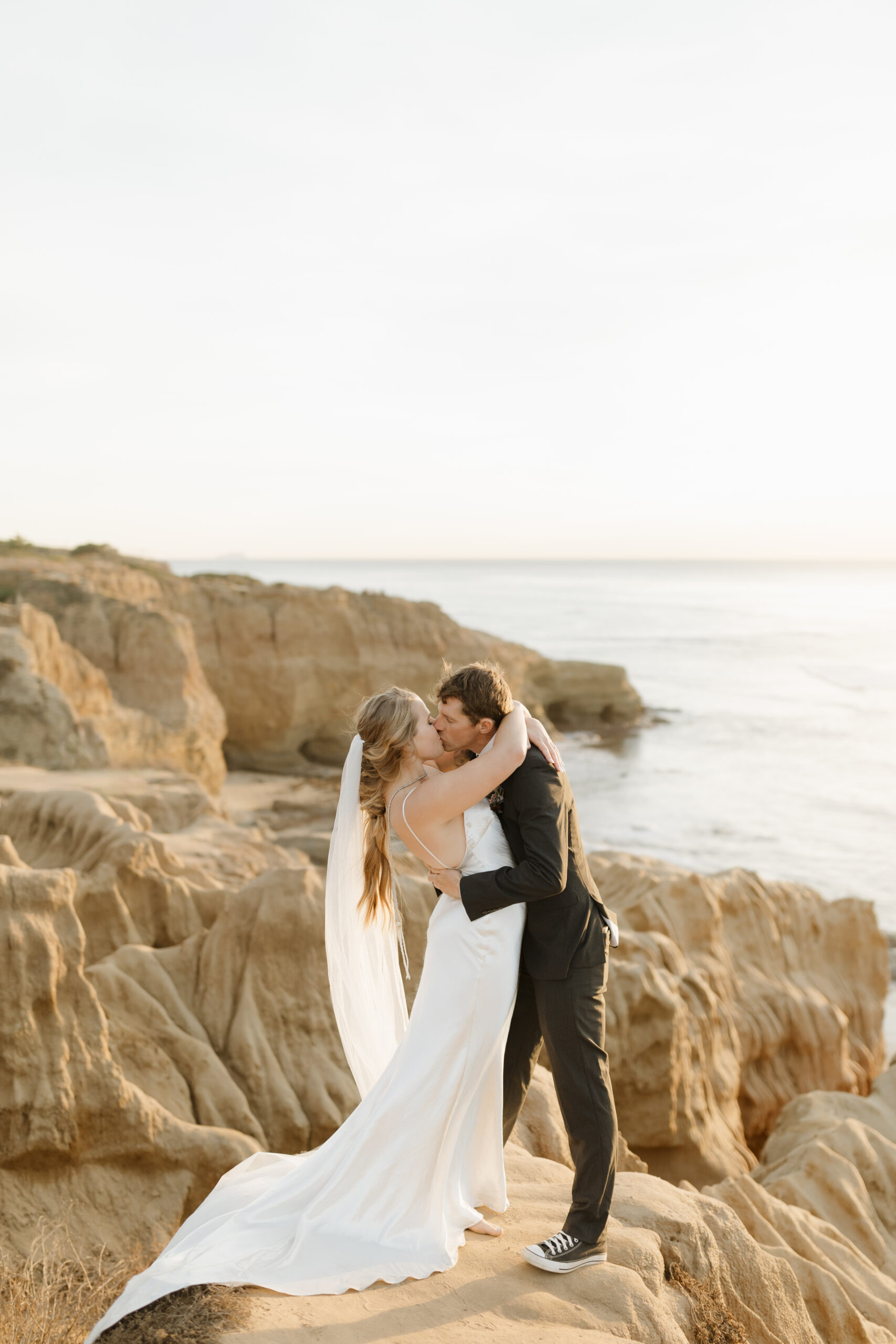 Wedding couple kissing cliffside