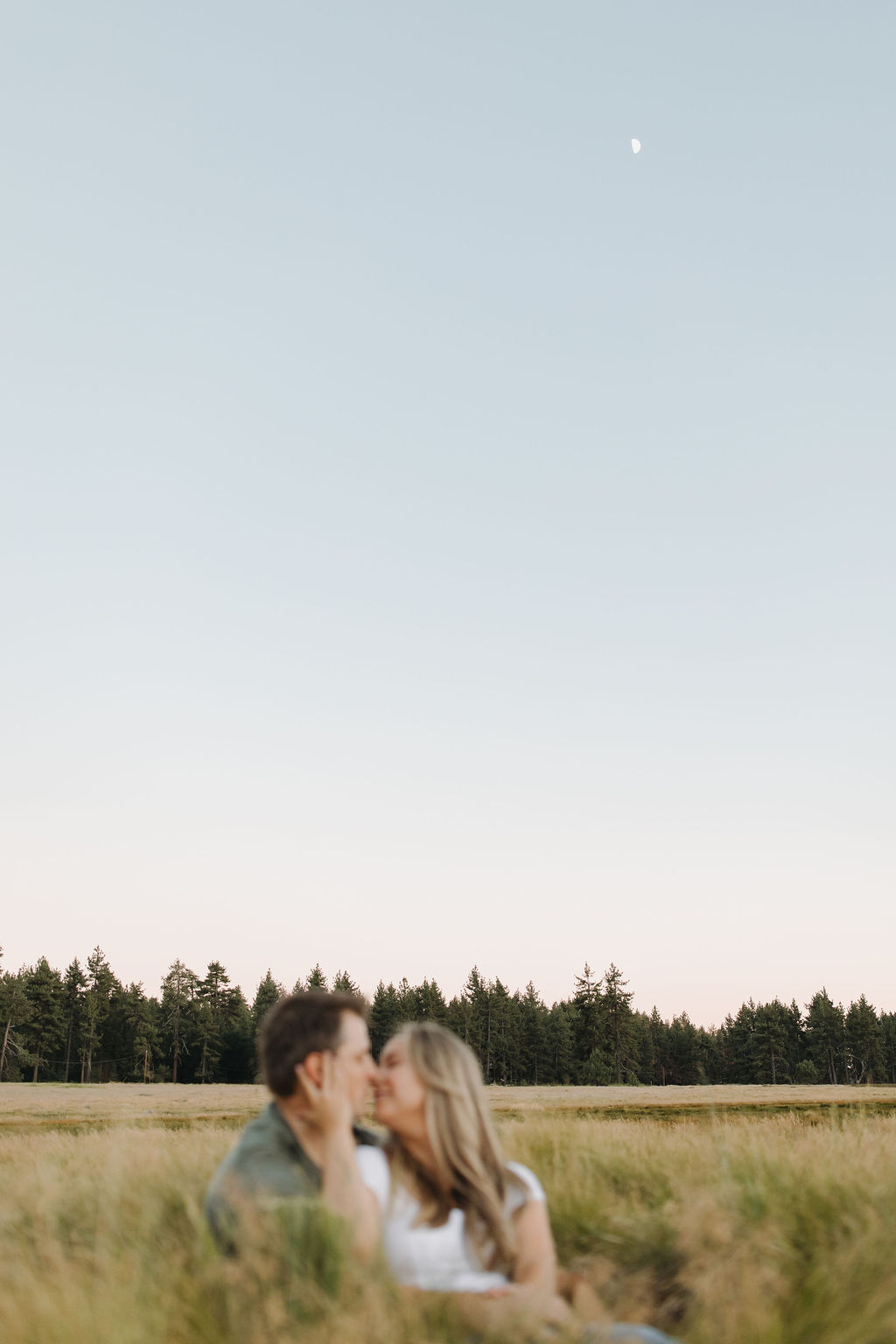 Blurry couple kissing with the moon in focus above them