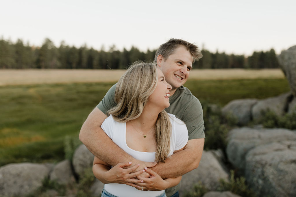 Man hugging woman from behind on some rocks