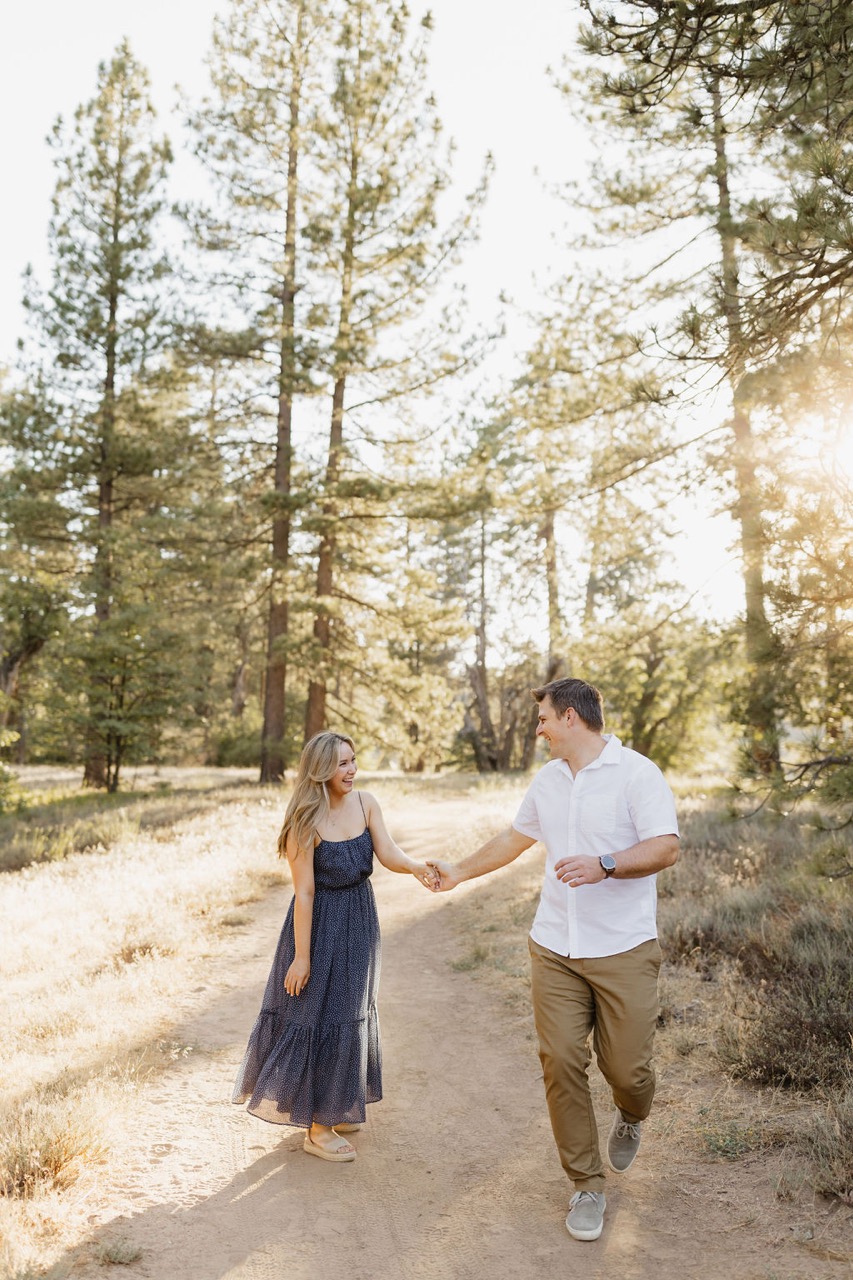 couple holding hands running in the forest