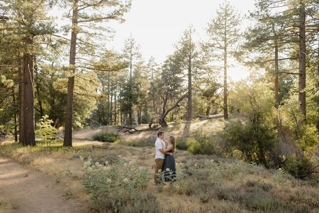 Couple in the forest surrounded by white flowere