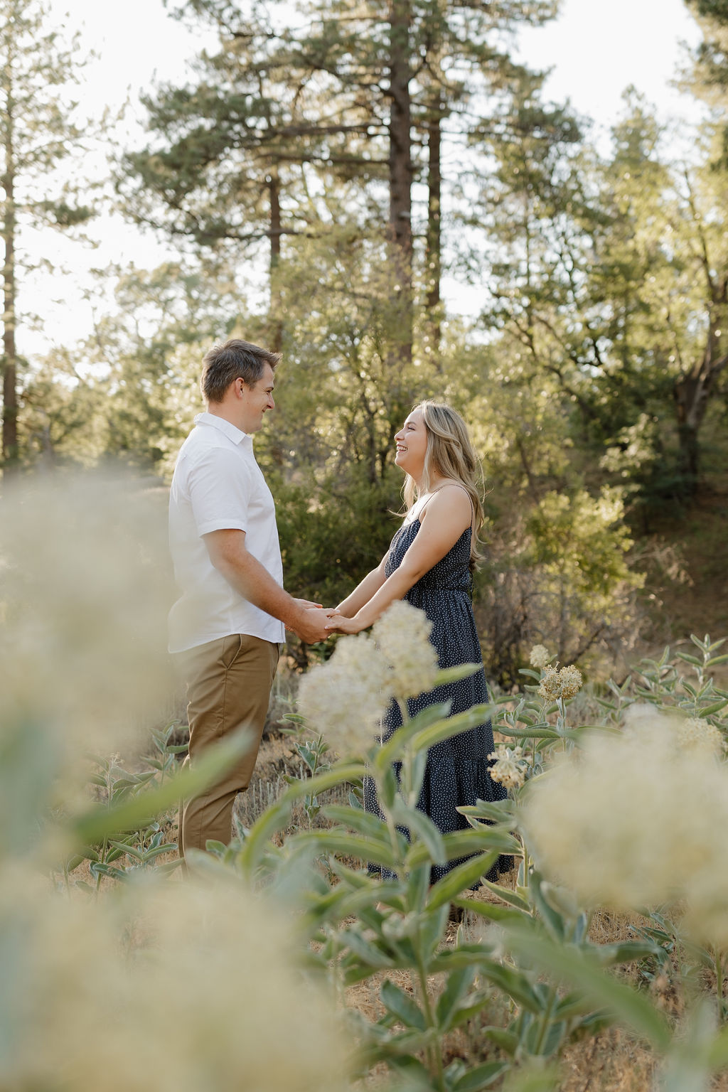 Couple holding hands behind white flowers