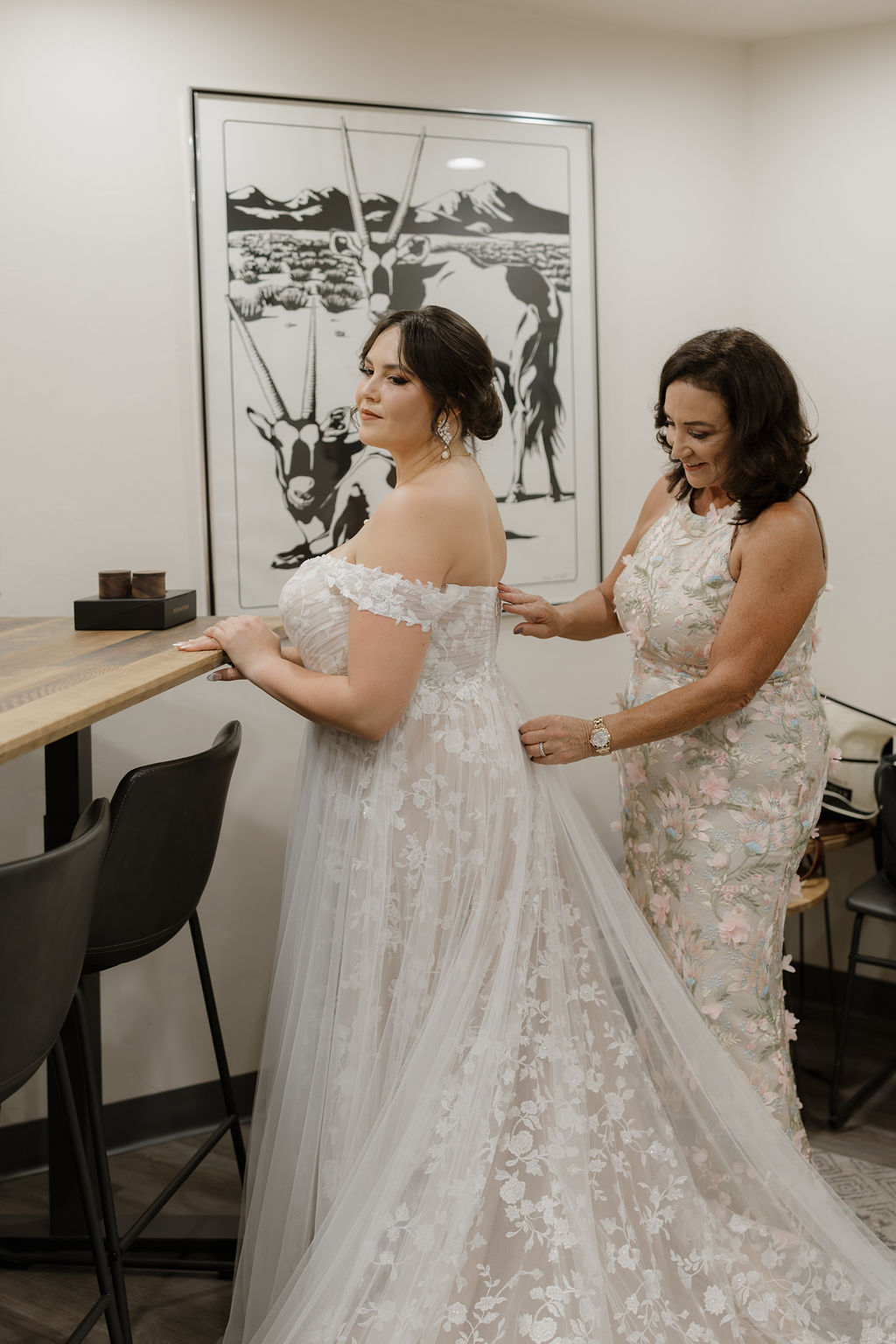 Mother helping adjust her daughters wedding dress. 