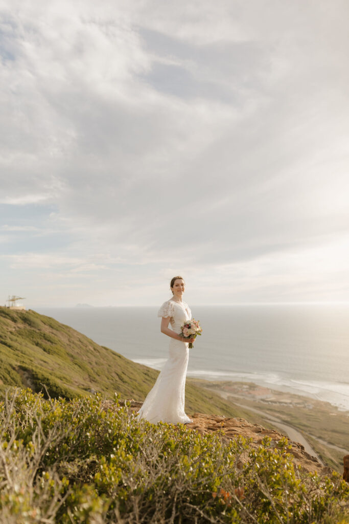 A bride wearing her wedding gown stands atop a California hillside following her cabrillo national monument wedding