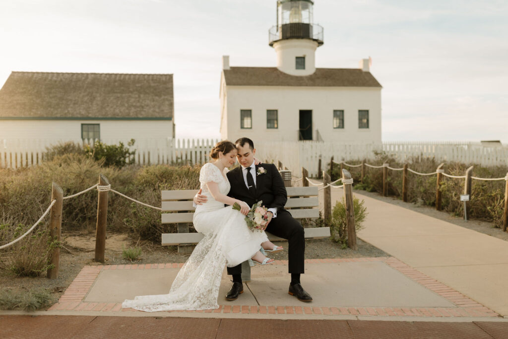A newlywed couple embrace on a bench near Point Loma Lighthouse following their southern california elopement
